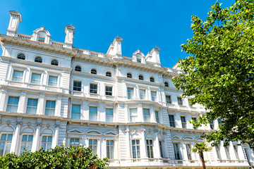 London, UK view of neighborhood district of Kensington by Lancaster high street upscale white luxury Hyde Park Hotel architecture and nobody with blue sky in summer