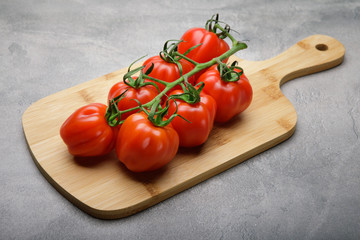 Red tomato on a cutting board on concrete background. Copy space. Fresh tomato wased for cooking