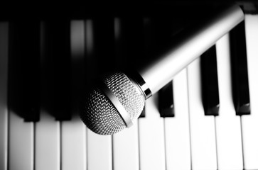 Microphone lying on the piano keyboards. Free time activities at home. Karaoke hobby. Creating music.