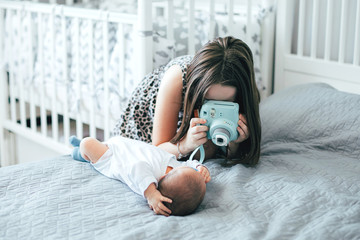 Older sister photographs, taking a picture the newborn's younger brother on bed in bedroomat home. Lifestyle family concept. Using technology concept - Powered by Adobe