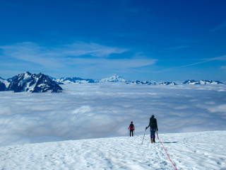 Fototapeta na wymiar Mountaineers descend mountain glacier above clouds