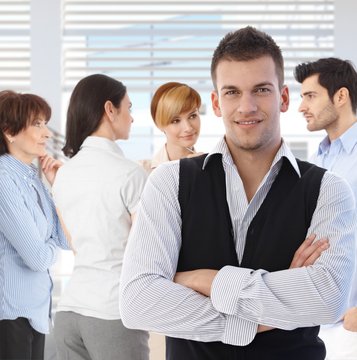 Portrait of young man at office in front of talking business team.