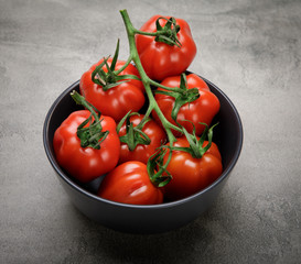 Red, ripe tomatoes on a dark background. Harvesting tomatoes. Top view of tomatoes in ceramics bowl