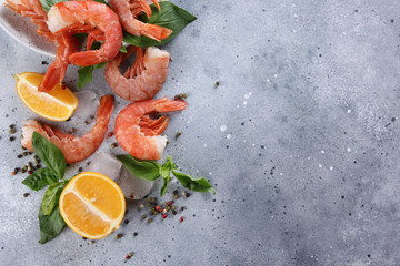 Seafood. Argentine prawns shrimps with lemon, basil, ice and spices  on a light grey background. Flatlay, top view. Background image, copy space