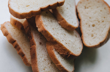 Scattered pieces of white dried bread lie on a white background. Photography, concept.