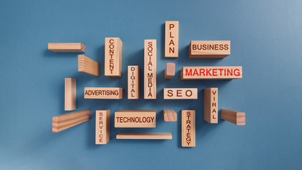 Wooden blocks with written words about digital marketing concept. Plain blue background.
