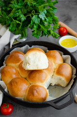 Traditional Ukrainian garlic bread buns in a cast-iron frying pan on a dark concrete background. Vertical orientation, copy space.