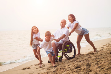 Disabled man in a wheelchair with his family on the beach.