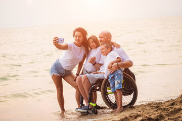 Disabled man in a wheelchair with his family on the beach.