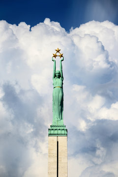 The Freedom Monument in Riga, Latvia, close-up. Blue sky with сumulus clouds in the background. Dramatic cloudscape. National landmark, travel destinations, sightseeing theme