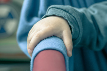 Children's hand on the arm of a chair. The boy is sitting on a chair