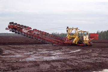 Peat or turf production: machine harvesting peat on the field 