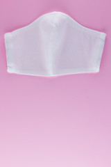 Protective gauze mask on a pink background. White antivirus mask. Handmade medical protective mask from cotton. Protective face mask made of gauze. Top view. Copy space
