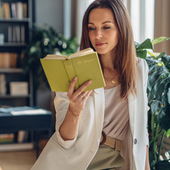 Portrait of young woman reading book at home