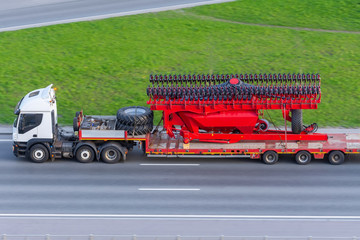 Transportation of large agro-complex machines for cultivating and sowing crops on long trailers by...