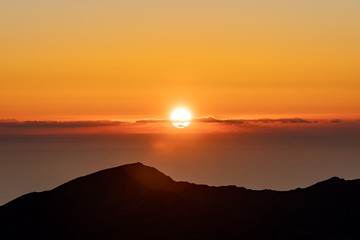 Sunrise over Haleakala Volcano on Maui in Hawaii with silhouetted mountain in the foreground