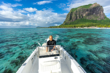 man drives a snow-white boat in the ocean against the backdrop of scenic mountains and clouds....