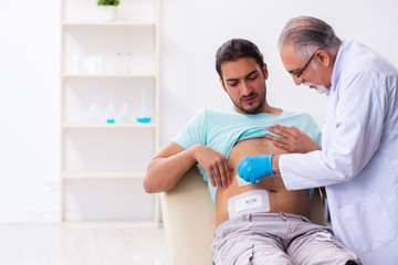 Fototapeta premium Injured young man visiting experienced male doctor