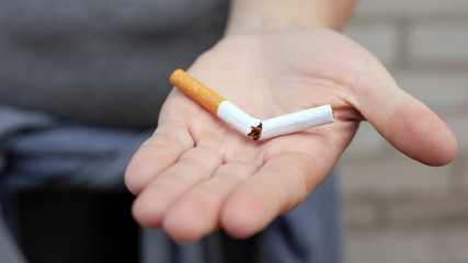 broken cigarette in hand, stop smoking concept, nicotine addiction.