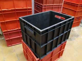 The big black plastic crate is surrounded by red plastic crates