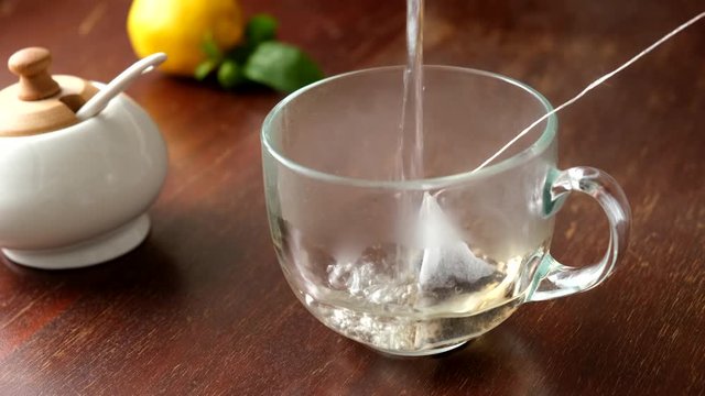 Brew black tea with tea bag in glass cup on wooden table