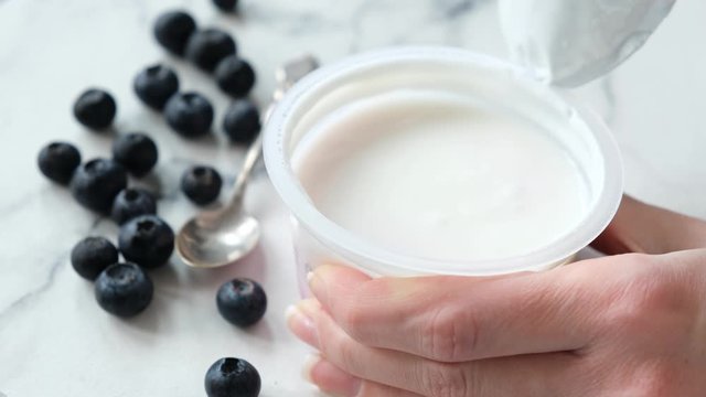 Opening plastic jar of yogurt