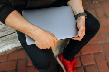 Young male working on his laptop computer in the city center. An independent person typing something in his document. chatting with friends over the internet, webcam