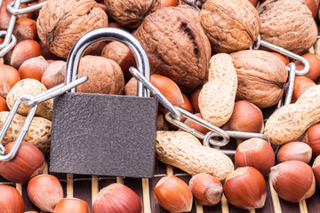 Padlock with chain on mix of nuts . Sanctions or embargoes, concept