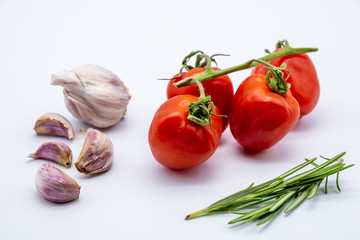 red cherry tomatoes with garlic cloves and rosemary on white background