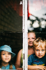 Two little cute lovely girls dramatic mood portrait. Children expressive facials. Countryside kids life. Sisters looking out of window. Young generation difficult childhood. Friends together at home.