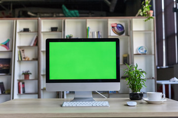 Computer desktop with mock-up green screen white background in office and Lovely plant in black pot
