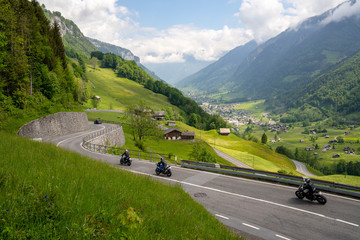 many motorcycles racing down the curvy Klausenpass mountain road in the Swiss Alps near Glarus - obrazy, fototapety, plakaty