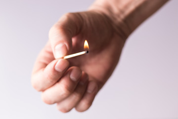 Burning match in the hand, flame of fire.