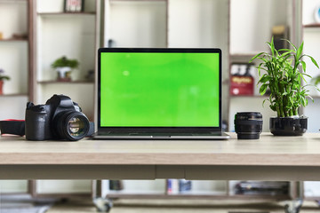 Laptop with mock-up green screen white background in office and Lovely plant in black pot