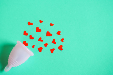 pink environmental menstrual Cup and red small hearts symbolizing blood on a blue background. protection during menstruation for women