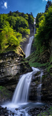 vertical panorama of the idyllic Diesbach creek waterfall in the Swiss Alps near Braunwald and Glarus in the spring © makasana photo