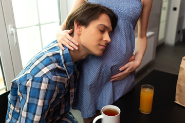 Happy man embracing pregnant woman in kitchen