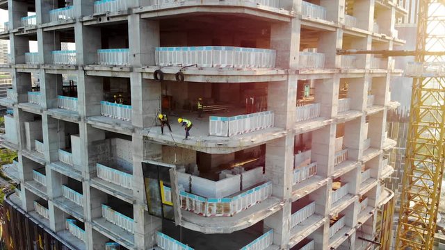 Workers are Installing the Precast Glass Panel on The Construction Site. Cladding of the Building by Curtain Walls.