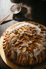 Vertical closeup isometric view of apple pie with powdered sugar sprinkle baked at home on dark wooden rustic table