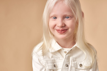 portrait of smiling albino child girl isolated over beige background, unusual interesting appearance of girl is mesmerizing, natural beauty concept