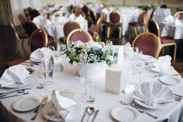 Festive table covered with white tablecloth, there are plates, silverware, napkins, glasses, Menu on the table