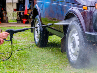 Car wash in the afternoon outdoors with a high-pressure apparatus. A powerful spray with water...
