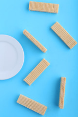 Tasty wafer sticks on Blue background, flat lay. Sweet food