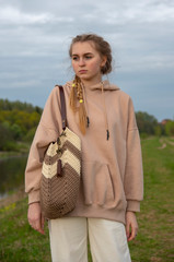Fashionable teen girl with a knitted bag on a walk along the river Bank.