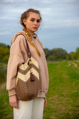 Fashionable teen girl with a knitted bag on a walk along the river Bank.