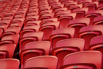 Fototapeta premium Empty red plastic seats in an empty stadium. Many empty seats for spectators in the stands. Empty plastic chairs seats for football fans.