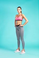 Ready for workout. Full length of young beautiful woman in sportswear looking at camera while standing against blue background. Sport and fitness