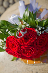 A bouquet of roses for a wedding. Bride and groom rings on a red wedding bouquet.