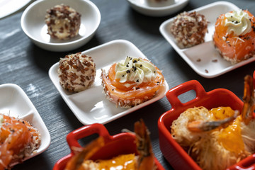 Salmon rolls, with cream cheese and butter, sprinkled with sesame seeds. Nearby are cheese balls in sesame seeds.