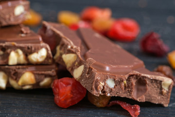 Milk chocolate with nuts, raisins, sec fruits. Close up, selective focus.